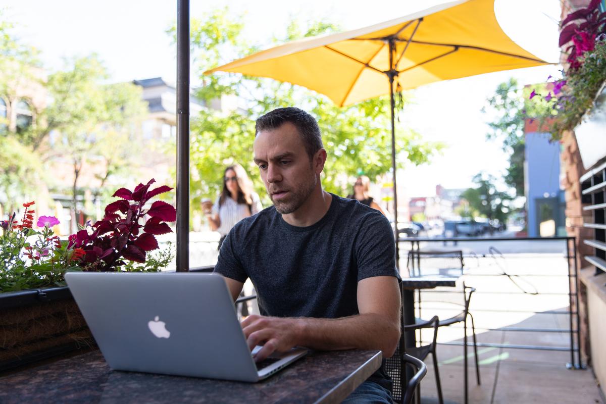 Man working on a laptop at an outdoor cafe