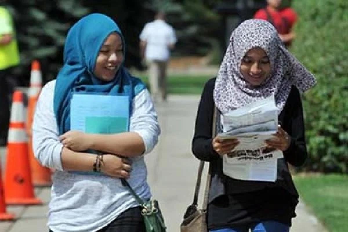 Two woman walking and carrying papers
