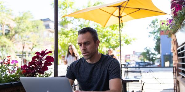 Man working on a laptop at an outdoor cafe