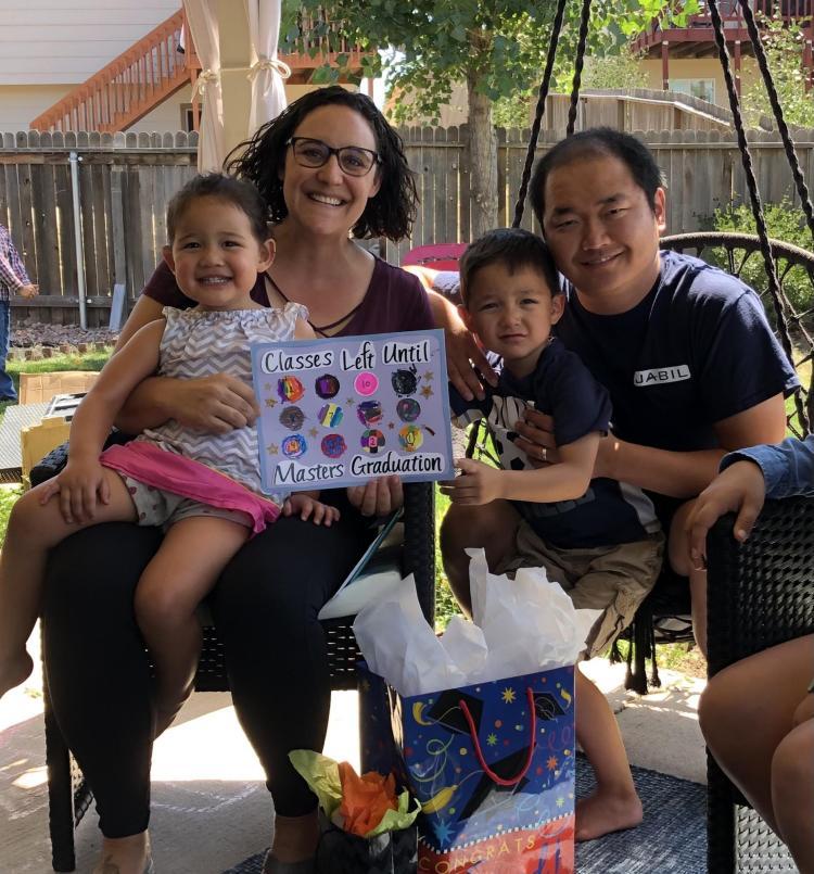 Woman and her family celebrating graduation with colorful poster