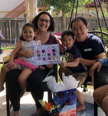 Woman and her family celebrating graduation with colorful poster