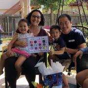 Woman and her family celebrating graduation with colorful poster