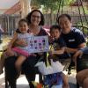 Woman and her family celebrating graduation with colorful poster